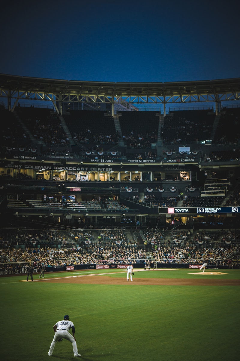 A baseball game scene at twilight showing players on the field and an engaged crowd, highlighting the atmosphere of live sports entertainment.